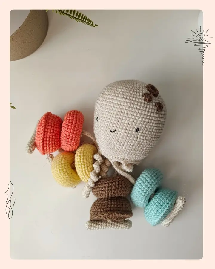 A playful crocheted octopus threading toy with a rattle hidden inside